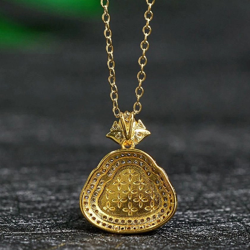 Reverse side of jade Buddha pendant featuring ornamental floral engraving and gold metal base