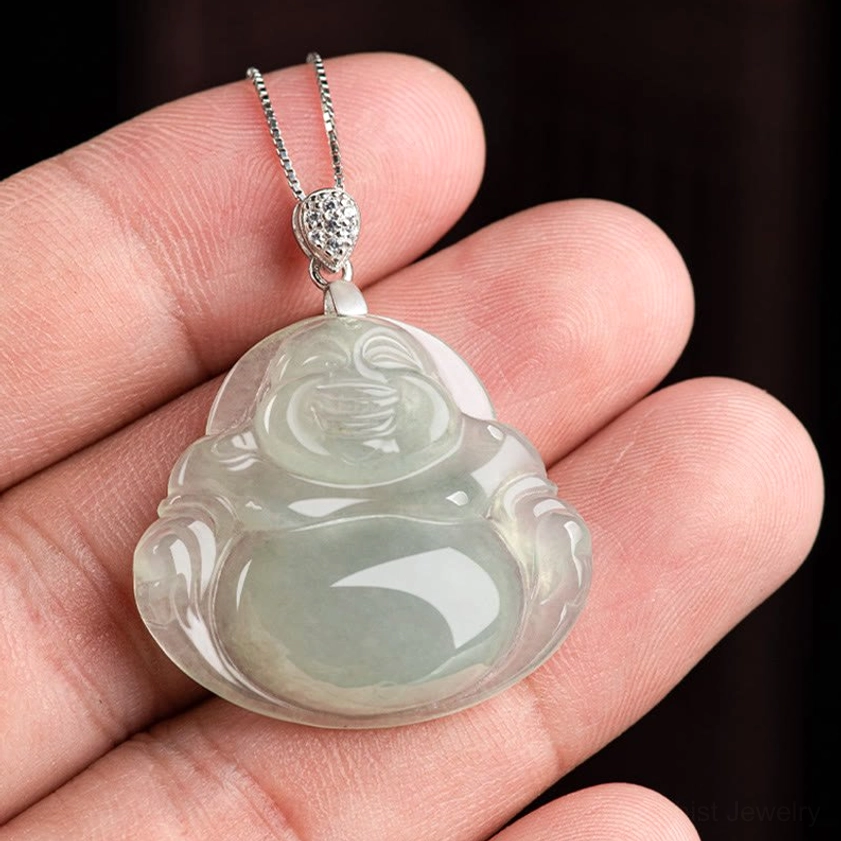 Natural jade Laughing Buddha pendant held in hands showing size and smooth light green stone texture