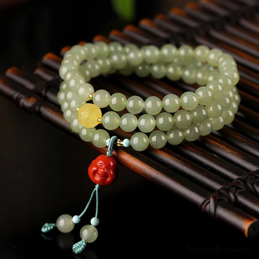108-bead jade laughing Buddha prosperity bracelet with amber accents and red agate pendant on bamboo tray, high angle view