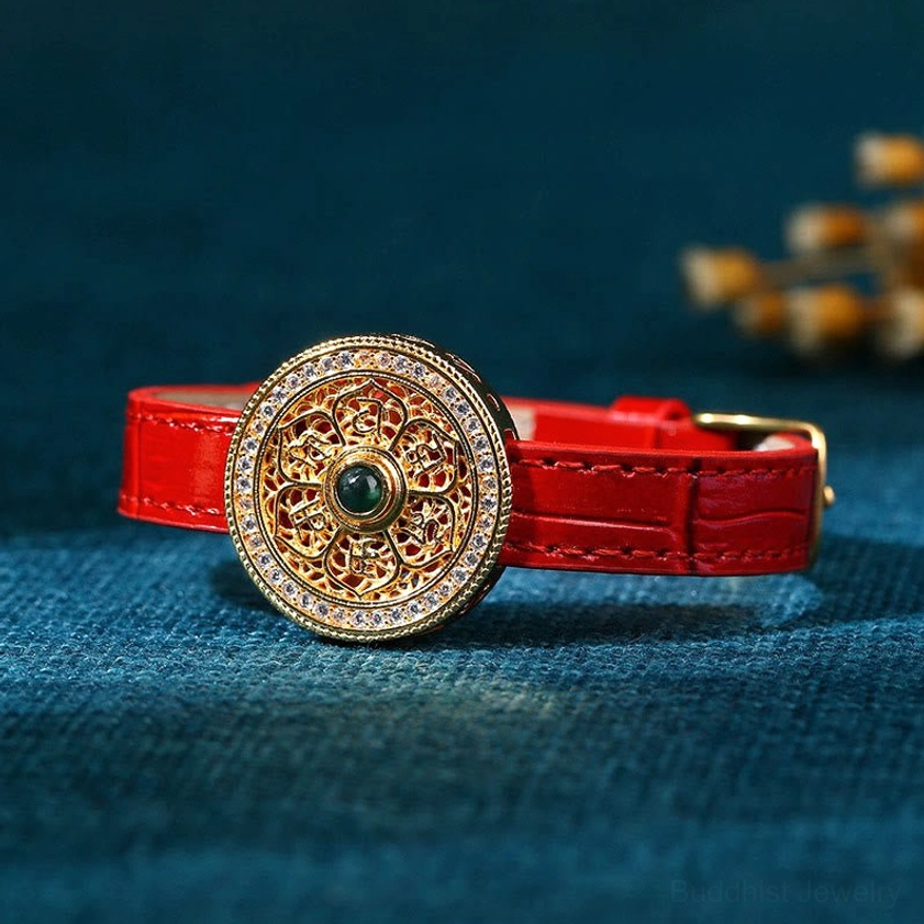 Side view of red leather Buddhist bracelet with central green jade stone in hollow gold Eight Treasures Compass charm