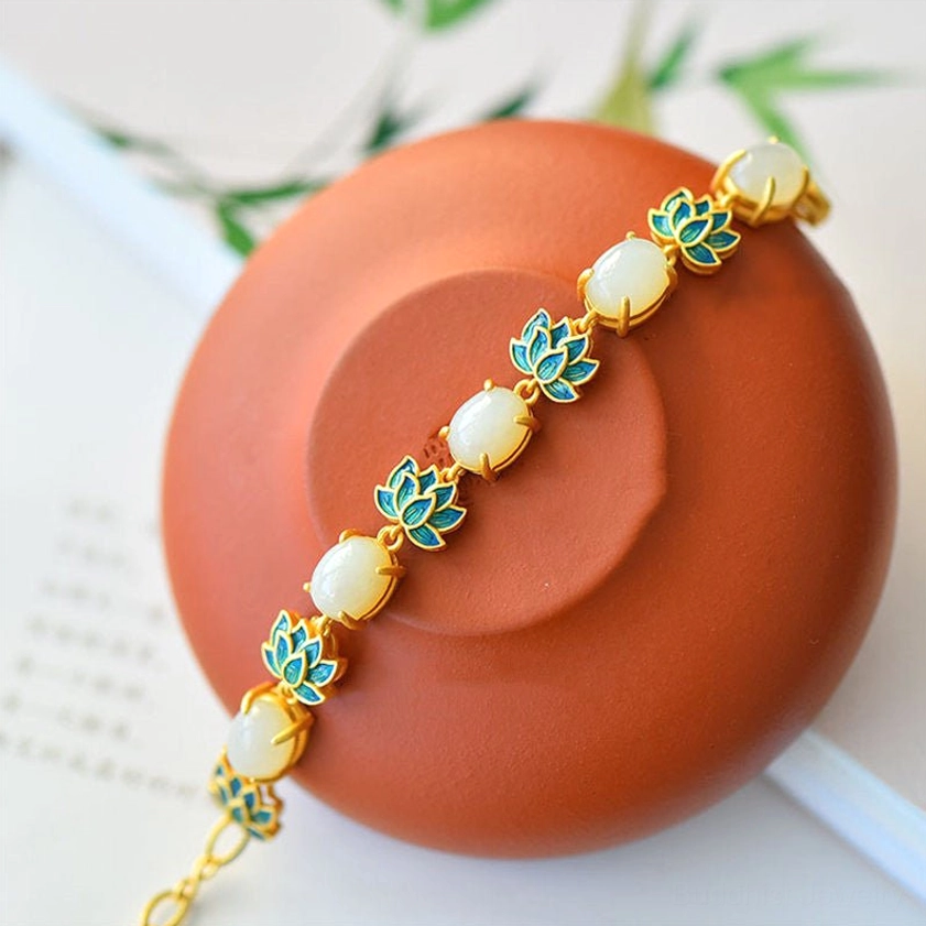 Close-up of smooth oval white jade beads and delicate blue enamel lotus charms on Buddhist protection bracelet