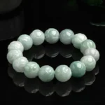 Natural jade lotus carving prosperity bracelet with carved lotus beads in light green and white jade tones on reflective black background