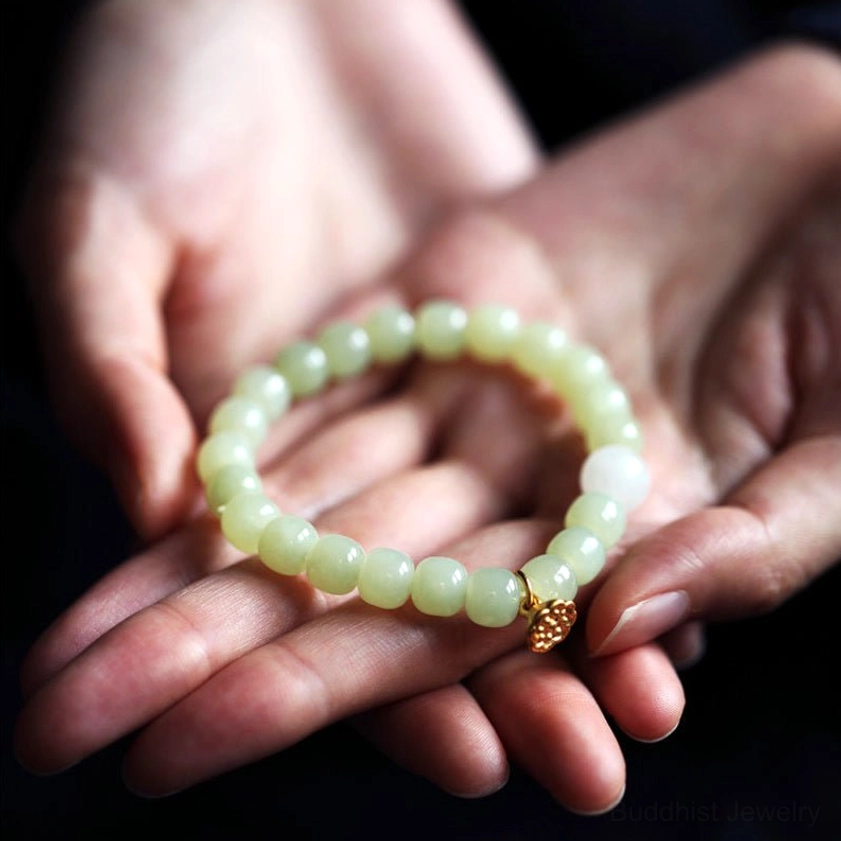 Light green matte jade beaded bracelet held in two palms showing round polished beads