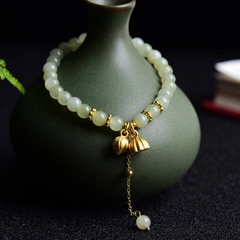 Hetian jade lotus bracelet wrapped around dark green ceramic vase, side view showcasing bead arrangement