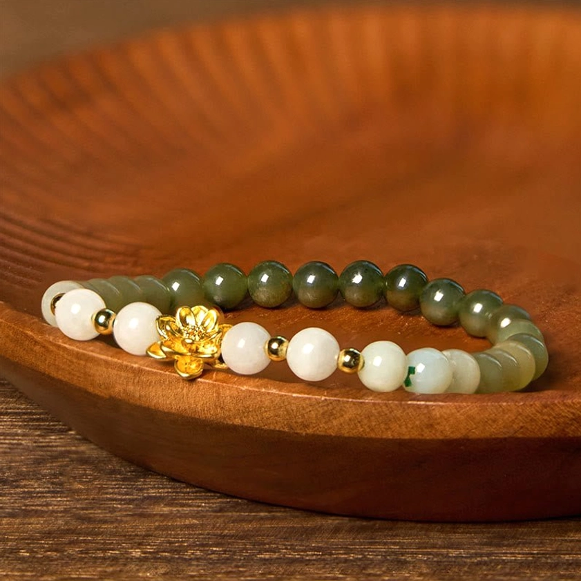 Premium Hetian jade bracelet featuring gradient beads and gold lotus centerpiece charm on dark wooden surface
