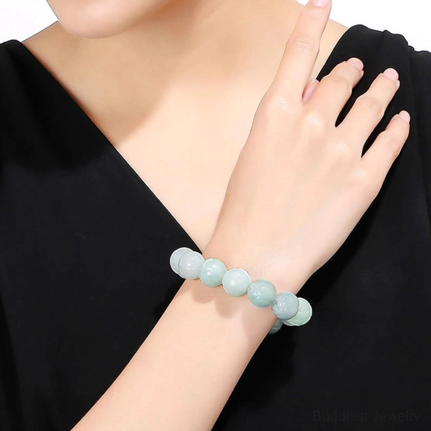 Woman wearing light blue and white jade round bead bracelet on wrist with black clothing background
