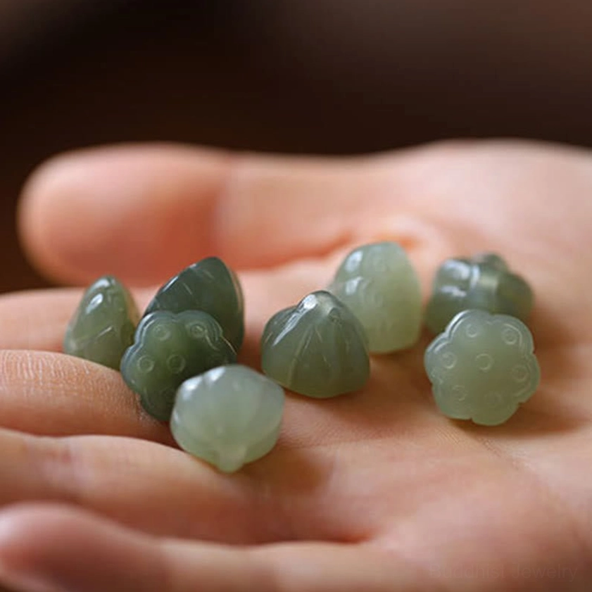 Multiple matte finish natural jade lotus charm carvings displayed on palm overhead view