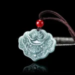 Natural jade lotus pendant necklace with brown rope and red bead, three-quarter front view showing intricate carved floral design and bluish-green stone color