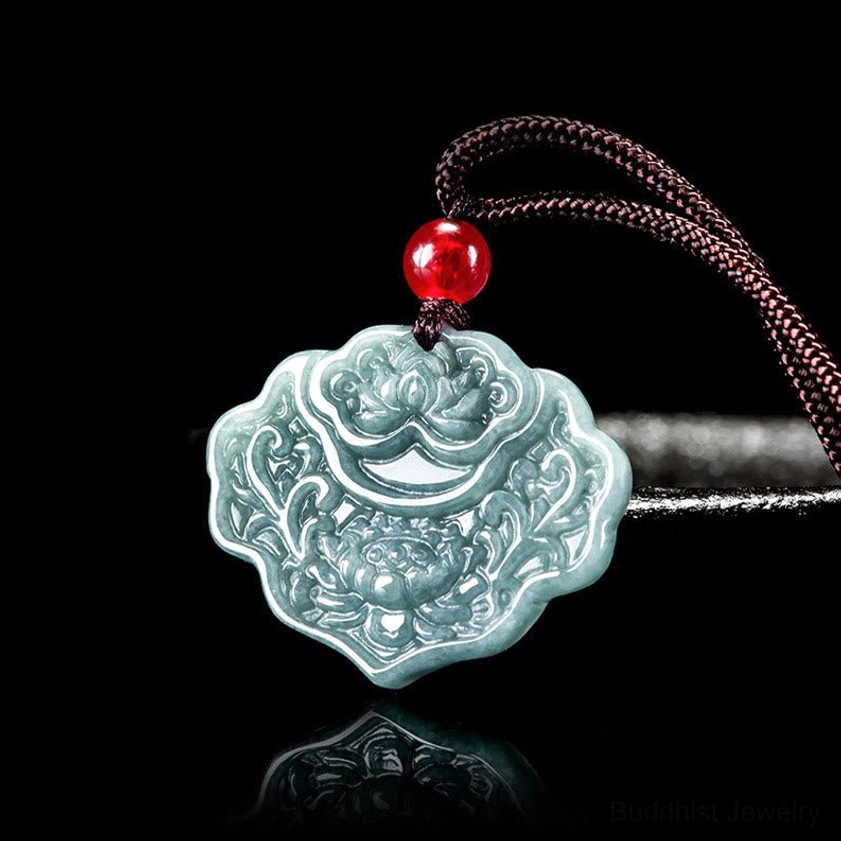 Natural jade lotus pendant necklace with brown rope and red bead, three-quarter front view showing intricate carved floral design and bluish-green stone color
