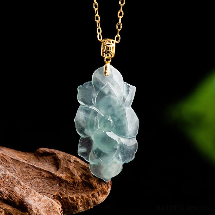 Three-quarter perspective of translucent cyan-blue jade lotus pendant on titanium steel chain showing sleek polished surface finish