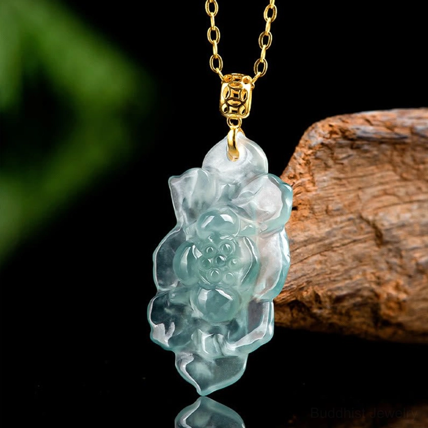 Side angle view of Buddhist jade lotus pendant displaying polished carved floral details and gold hardware against natural green background
