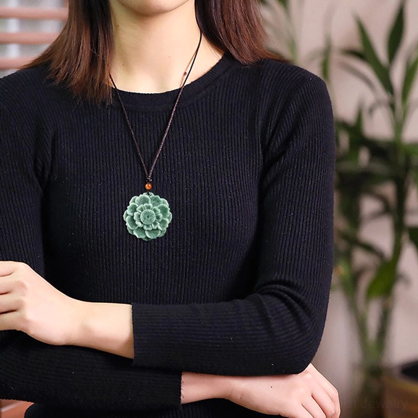 Woman wearing green jade lotus Buddhist necklace pendant with brown cord, styled with black knit top for everyday wear