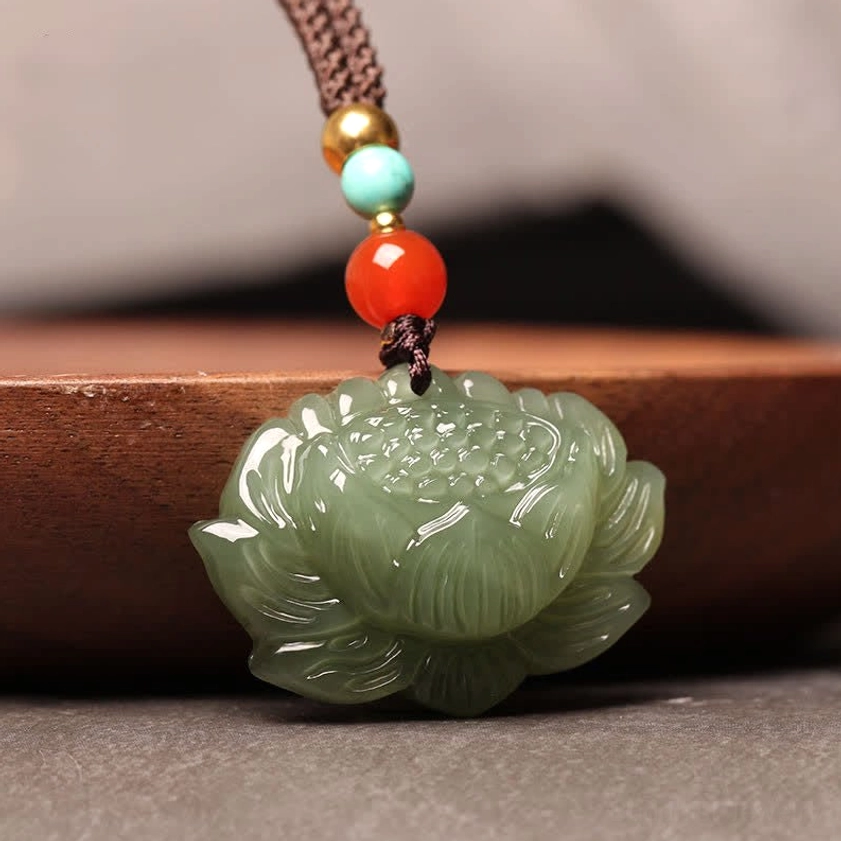 Cyan jade lotus necklace pendant right side angle view showing smooth carved lotus silhouette and profile on neutral wooden background