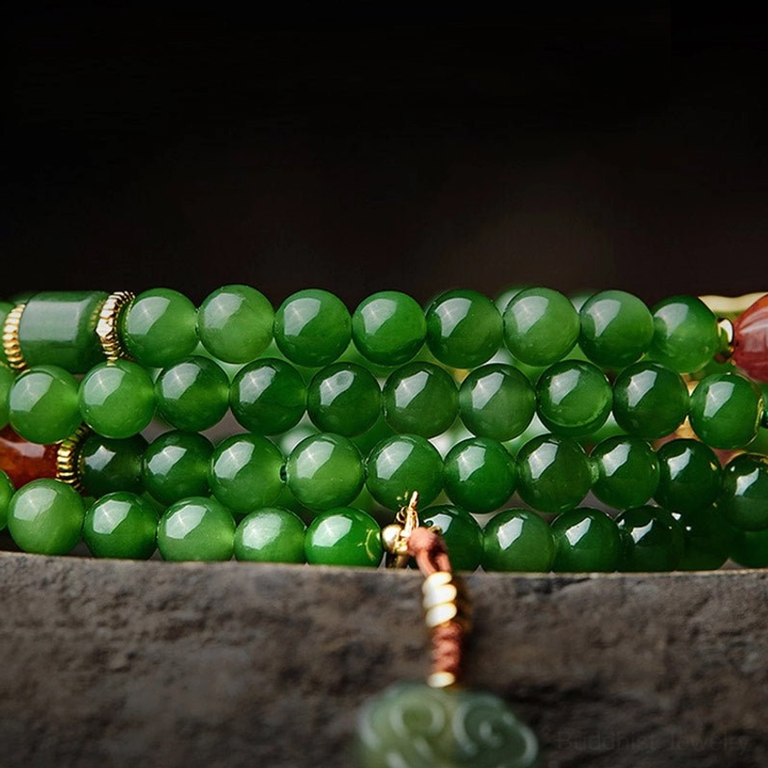 Close-up flat lay of smooth round cyan jade beads with 925 silver spacers and cloud-shaped jade tassel