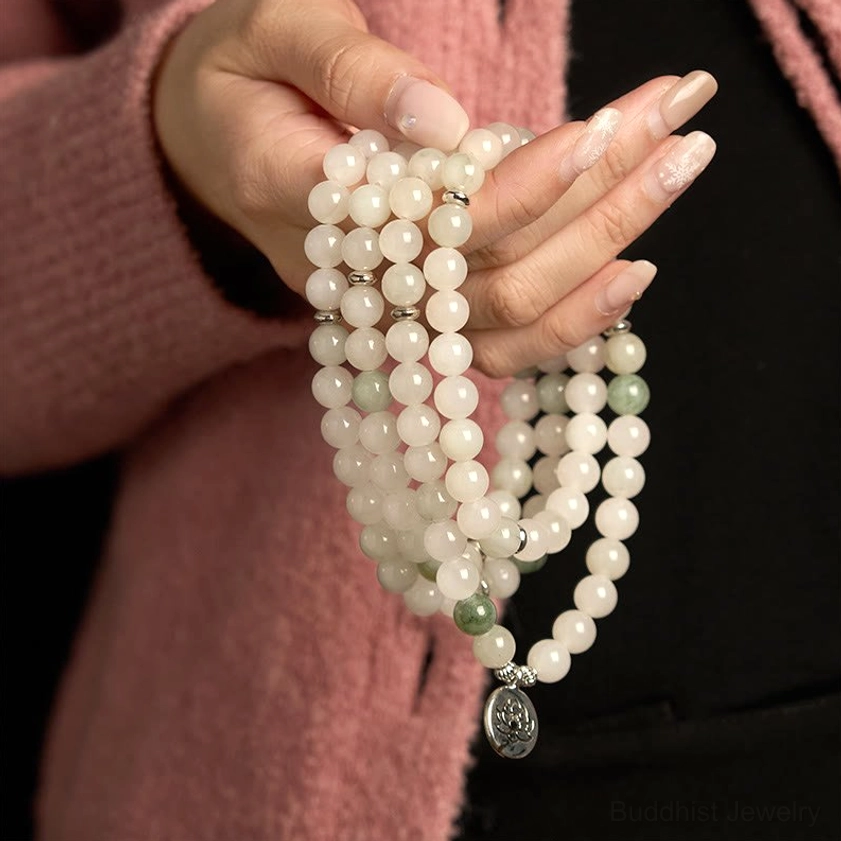 Close-up of hands holding jade mala bracelet with lotus pendant, showing smooth matte finish and bead texture