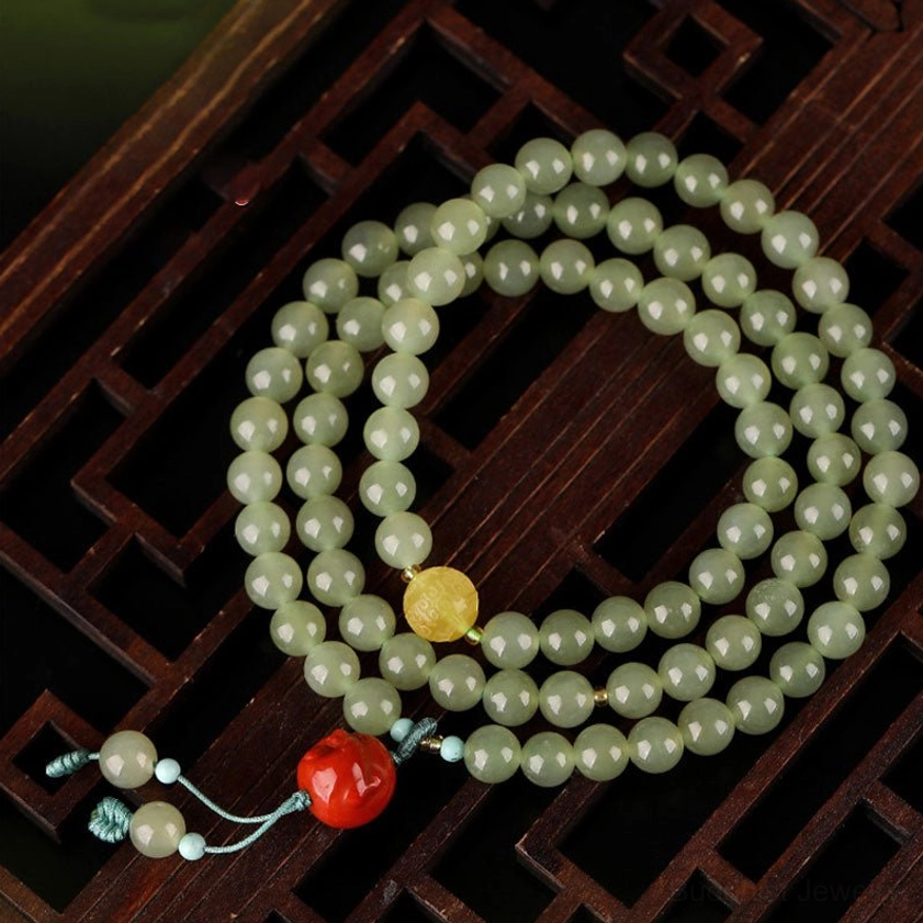 Jade prayer beads mala bracelet with red laughing Buddha charm and amber spacer on carved wooden lattice background