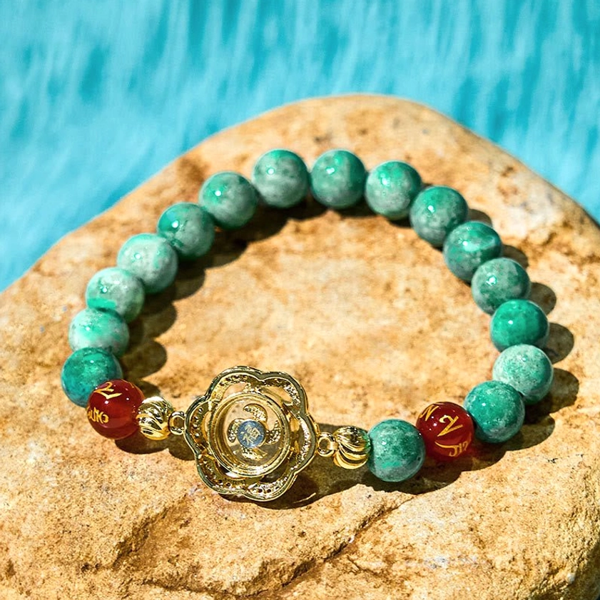 Teal jade Buddhist bracelet with silver-gold rotating flower charm and crystal accents on stone