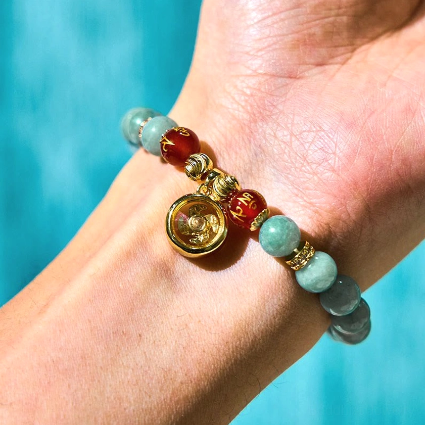 Buddhist jade bracelet worn on wrist featuring gold-plated rotating spinning charm and natural jade beads in close-up side view