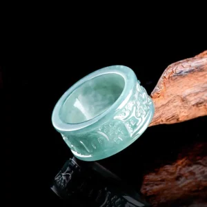 Natural jade Om Mani Padme Hum Buddhist ring with hand-carved mantra, light cyan jade stone displayed on wooden prop showing engraved spiritual inscription