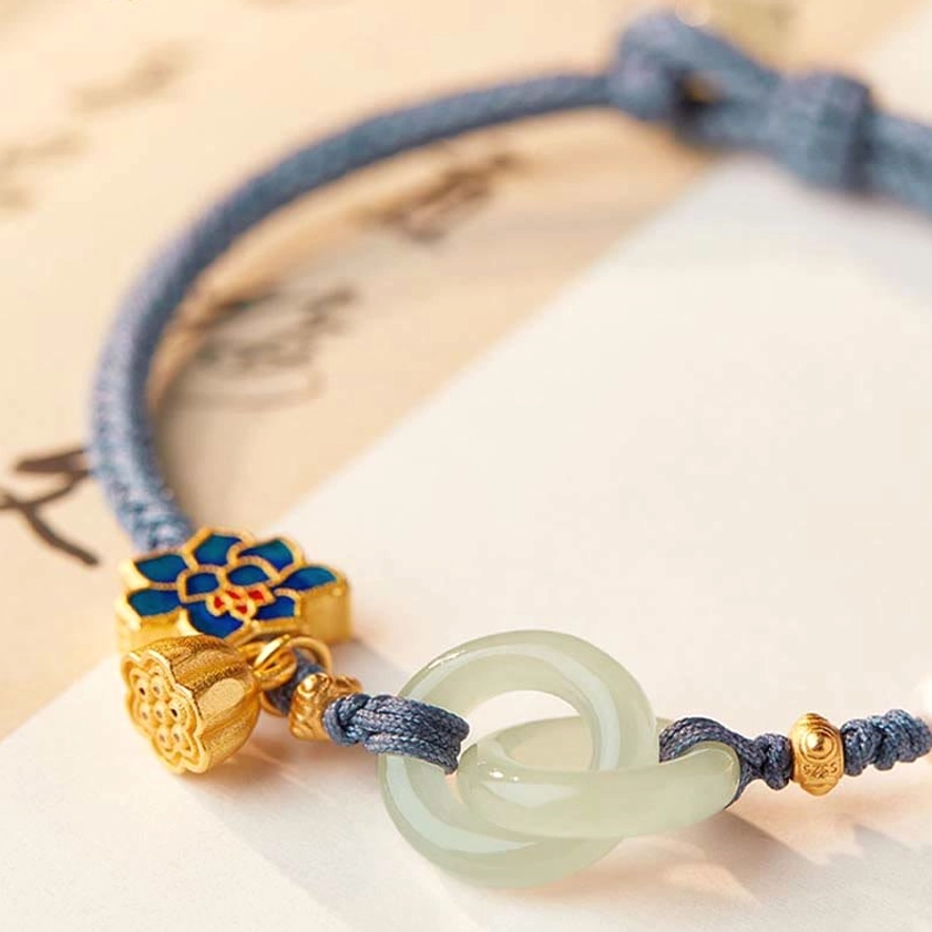 Buddhist fortune bracelet in red variant showing jade peace buckle, lotus charms, and braided rope detail