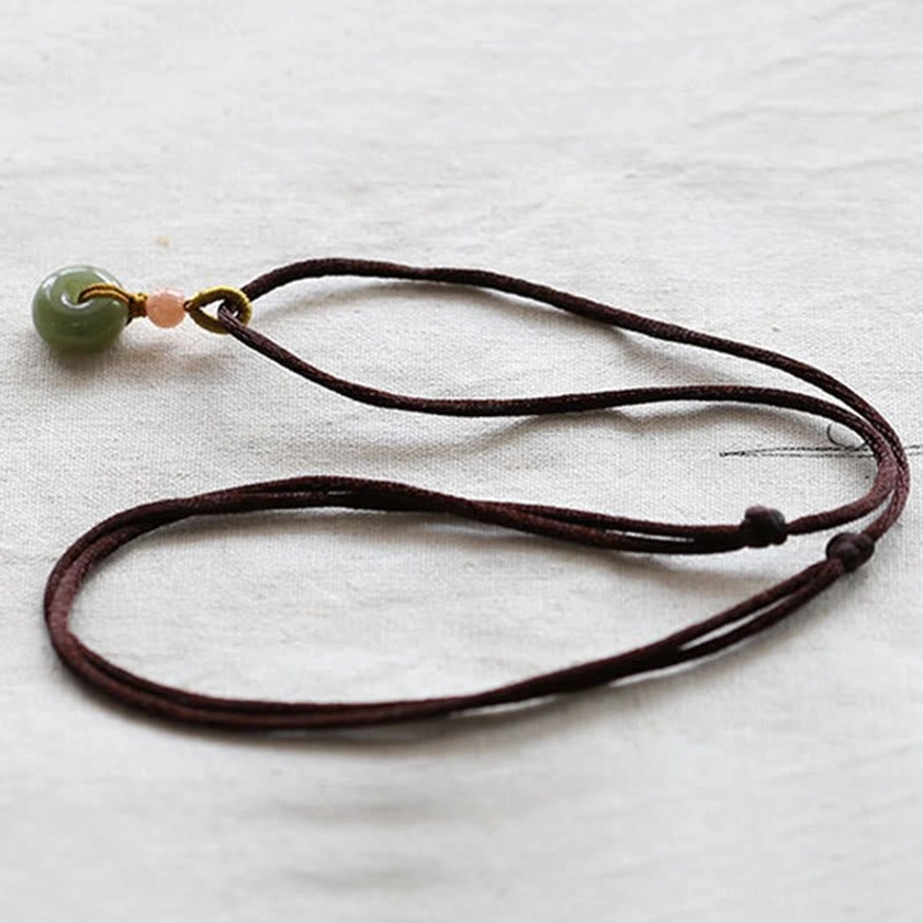 Handcrafted jade peace buckle pendant necklace detail showing knotted cord craftsmanship