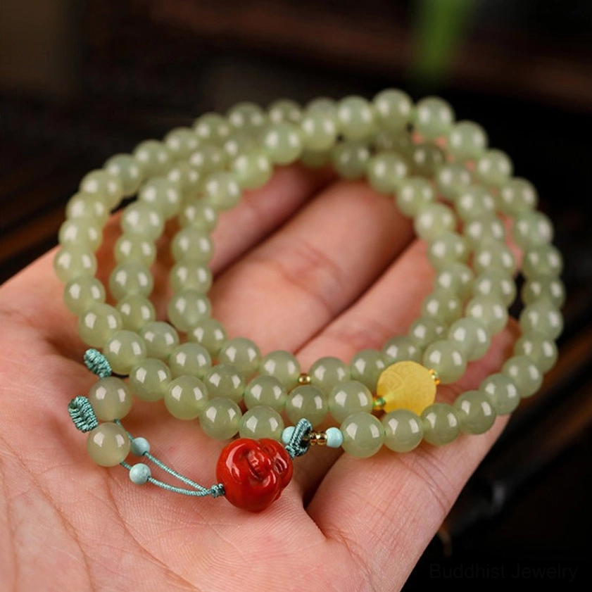 Multi-turn jade prayer bracelet worn on palm, showing triple-layer wrap with light green beads and red Buddha pendant