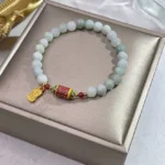 Natural jade prayer wheel Fu character bracelet displayed in luxury gift box with enamel prayer barrel and gold pendant