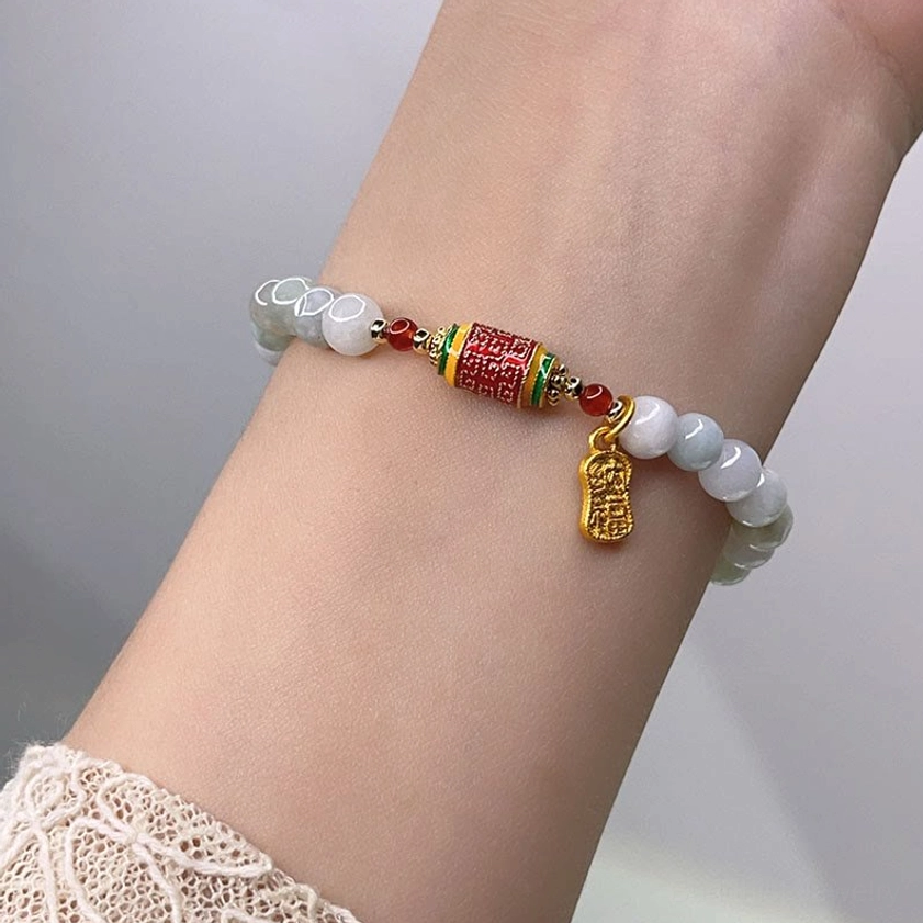 Jade Buddhist prayer wheel bracelet worn on wrist with lace cuff showing comfortable fit and charm placement