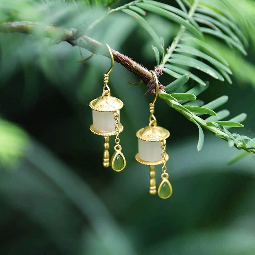 925 sterling silver jade prayer wheel drop earrings hanging outdoors with pine branch backdrop, showing gold and green teardrop pendant charms