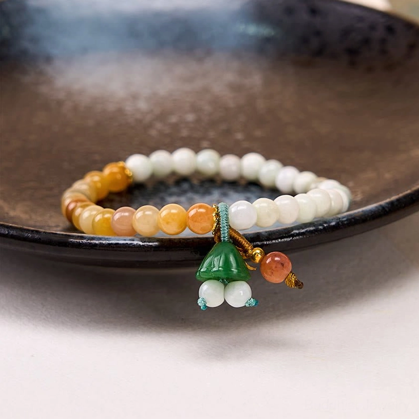 Jade quartzite bracelet displayed on dark ceramic plate, eye-level shot showing neat bead arrangement and lotus pendant