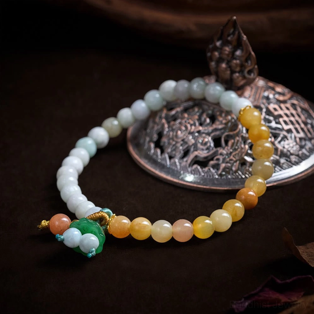 Overhead flat lay view of jade quartzite bracelet with braided decorative knots and gradient colored beads on vintage metal background