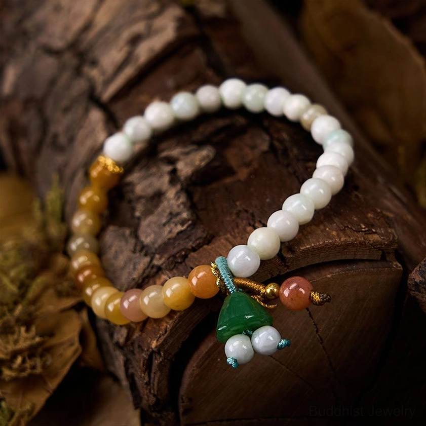 Top-down shot of natural jade quartzite bracelet with green lotus charm resting on wooden bark surface