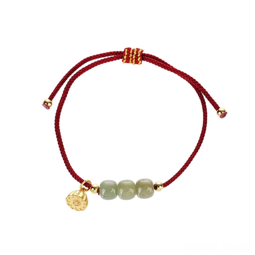 Top-down view of red string jade bracelet on plain light background showing adjustable sliding knot design, three jade beads, and gold flower charm