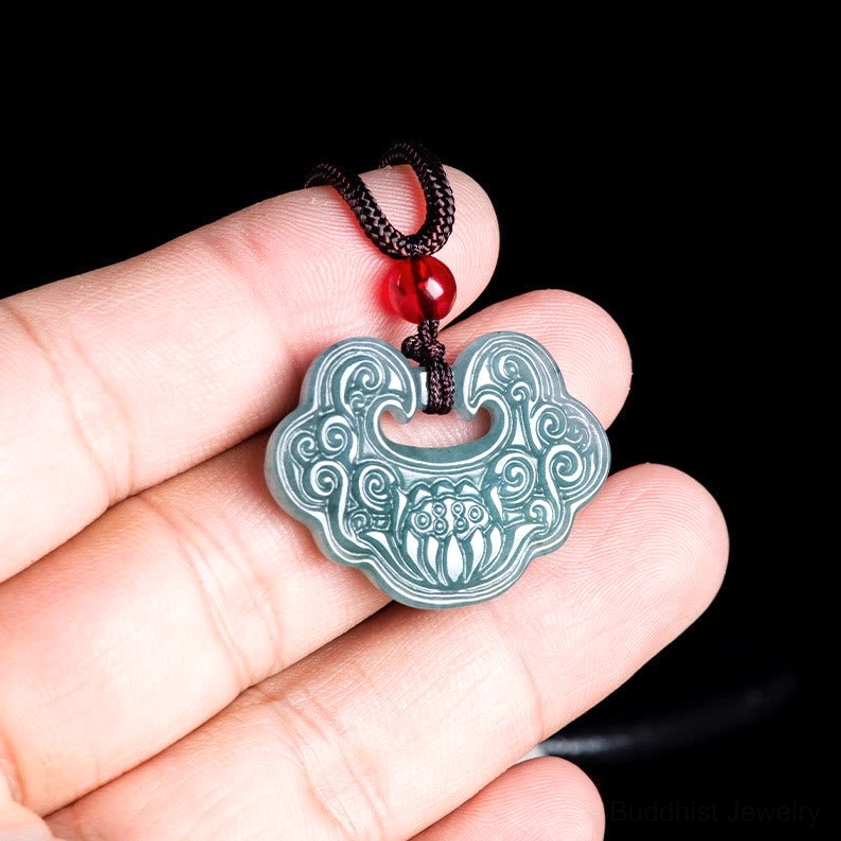 Jade Ruyi lock pendant held in hand showing carved cloud and floral Buddhist motifs relative size
