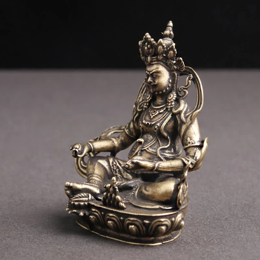 Yellow Jambhala Buddha statue side profile showing deity carved features and hand accessories with bronze texture
