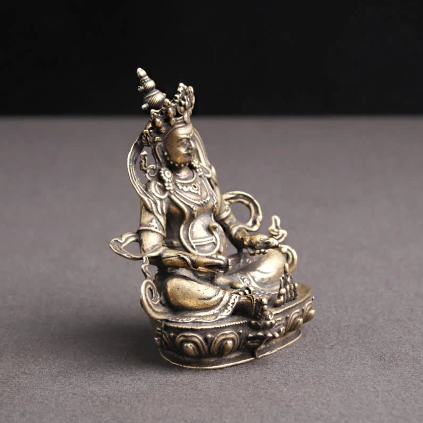 Yellow Jambhala Buddha statue left three-quarter profile showing crowned deity face and intricate lotus pedestal