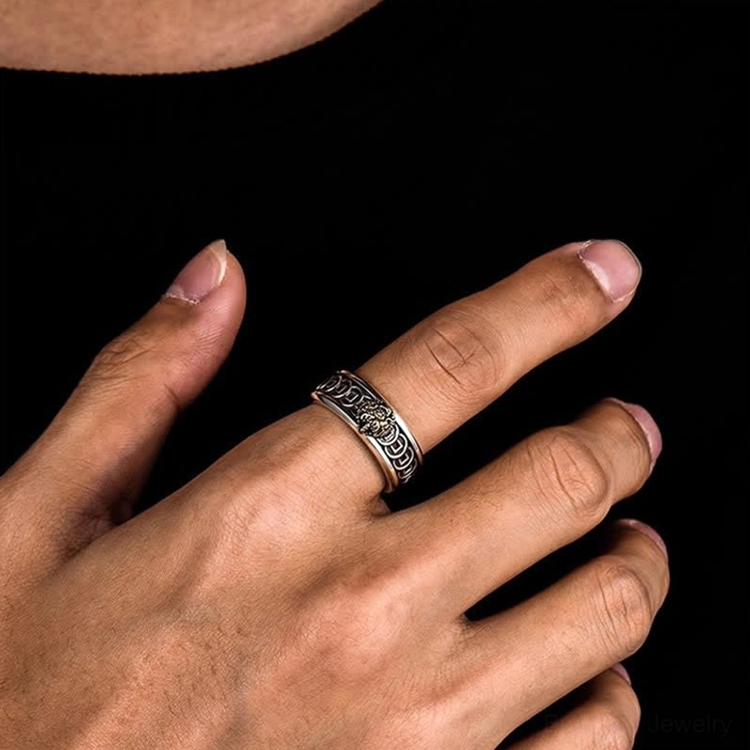 Buddhist protection ring worn on index finger close-up side view showing vintage engraved finish