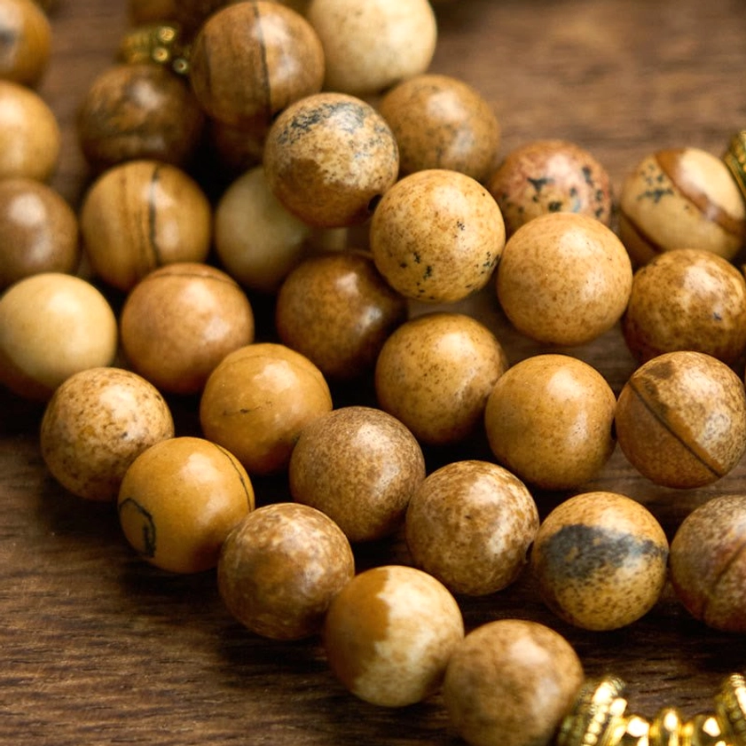 Close-up macro shot of picture jasper beads showing natural stone grain texture and gold spacers