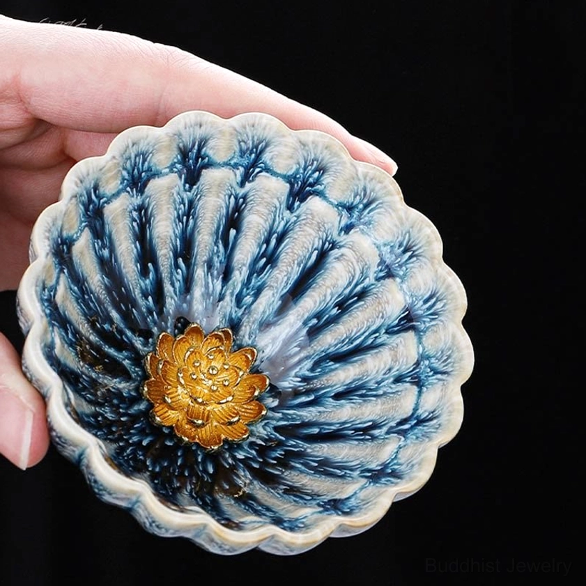 Lotus jian zhan tea cup handheld top down view showing blue kiln glaze and gold floral detail