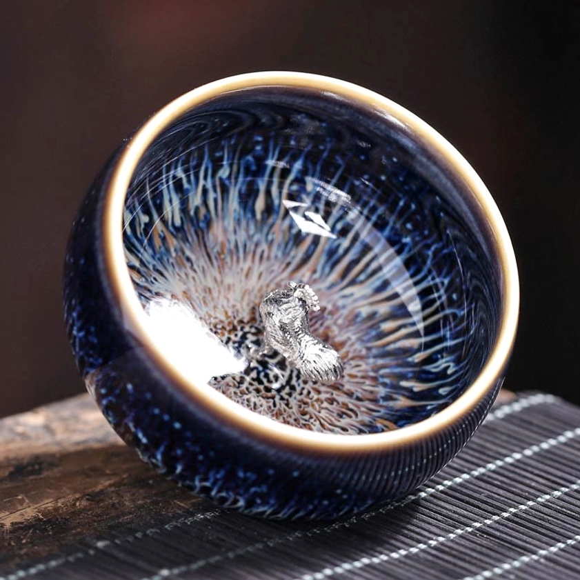 Jian Zhan ceramic tea cup with zodiac sign ornament, showing natural glaze variation and artisan handcraft quality