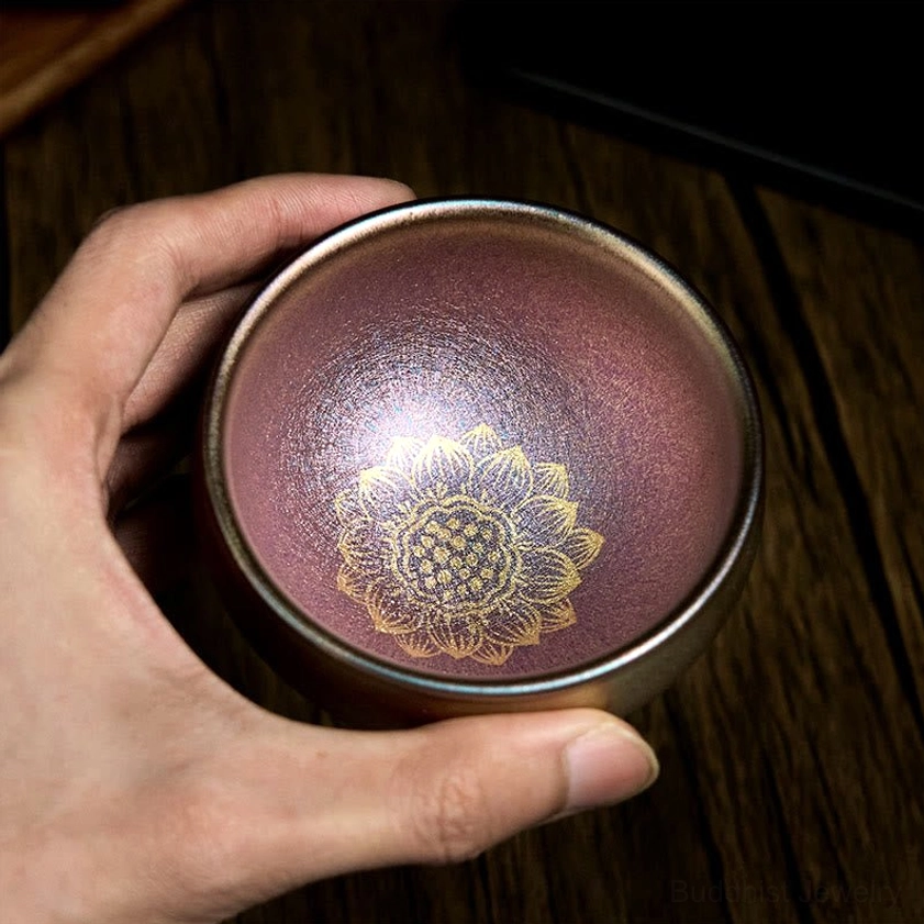Handcrafted Jianzhan golden lotus ceramic teacup with glossy iridescent finish held at eye level - detailed glaze pattern view