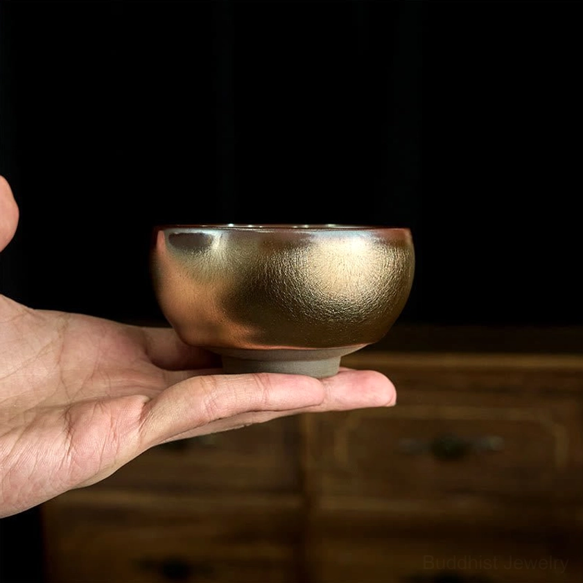 Chinese Jianzhan ceramic teacup with smooth bronze-gold glazed surface and rounded cup body, side view