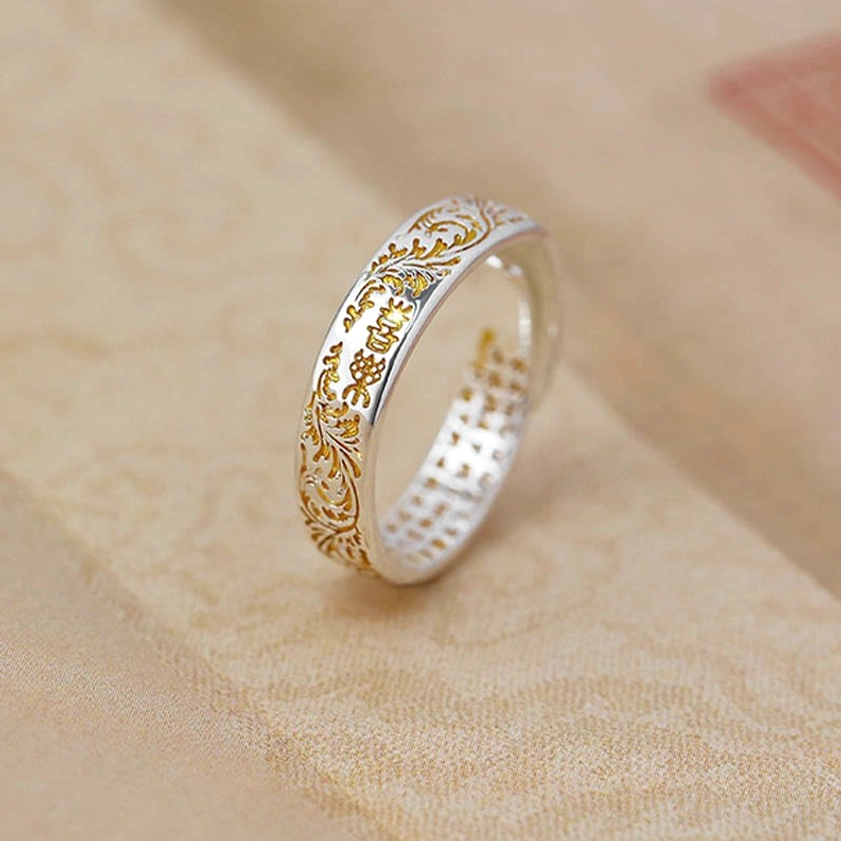 Side view of handcrafted adjustable joy and lotus Buddhist ring with silver base and gold floral pattern details