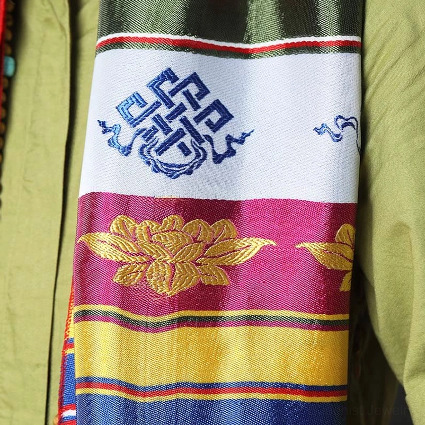 Close-up of Buddhist Khata scarf displaying golden lotus pattern and endless knot embroidery on colorful striped borders