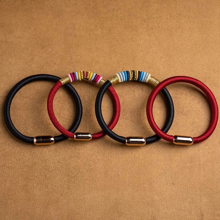 Four handmade king kong knot bracelets in red and black cord arranged overhead view
