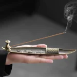Buddhist koi fish boat incense burner held in hand with smoking incense, bronze metal with embossed fish design