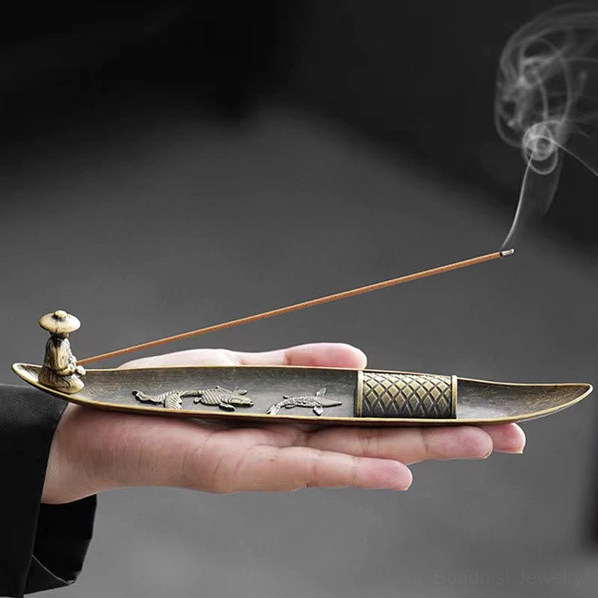 Buddhist koi fish boat incense burner held in hand with smoking incense, bronze metal with embossed fish design