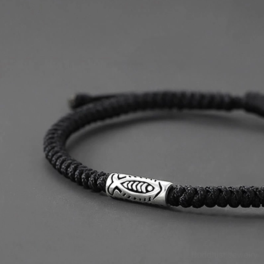 Close-up side view of hand-braided black koi fish bracelet highlighting detailed silver charm and twisted weave texture
