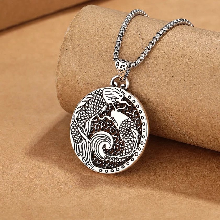 Unadorned copper koi fish pendant necklace showing carved filigree pattern without enamel on paper background