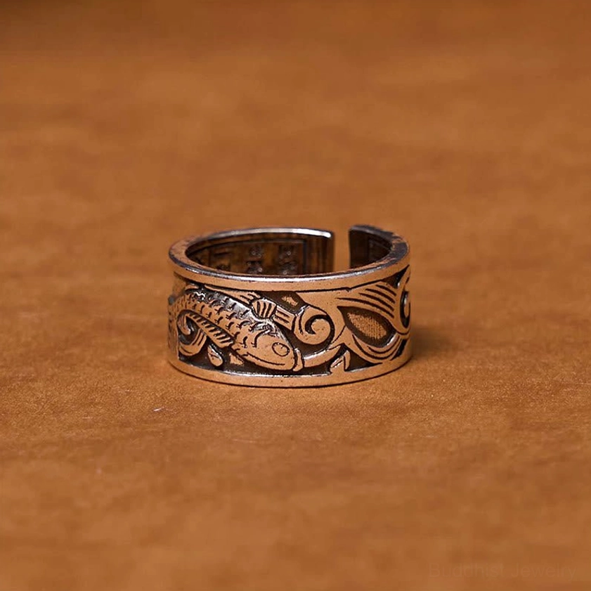 Koi fish engraved buddhist ring front view on brown leather background, antique silver finish with embossed carp motif